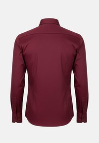 Camisa de manga larga burdeos con cuello clásico, textura suave, corte entallado y puños abotonados, que presenta un dobladillo curvado.