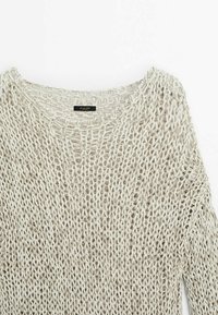 Lichtbeige gebreide trui met een losse, open structuur. Heeft een ronde halslijn en verlaagde schouders. Label zichtbaar aan de binnenkant van de halslijn.