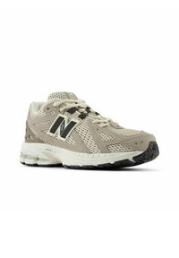 Beige mesh hardloopschoen met een versterkte neus, zwarte accenten en een gestructureerde zool. Beschikt over een gevoerde tussenzool en een vetersluitingenontwerp.