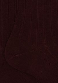 Calze rigate color bordeaux realizzate in tessuto morbido, caratterizzate da un motivo testurizzato con fini linee verticali e un tallone rinforzato.