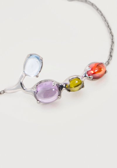 Collana con catena d'argento con quattro pietre ovali in azzurro chiaro, viola, giallo e arancione, incastonate in un design fluido e connesso.