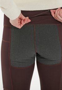 Leggings taille haute en bourgogne avec des panneaux en maille grise texturée et des coutures contrastantes ; ceinture ajustable avec un système de maintien sécurisé.