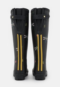 Bottes de pluie en caoutchouc noires avec des rayures jaunes, décorées de motifs colorés de libellules et d'insectes. Elles présentent des sangles ajustables en haut.