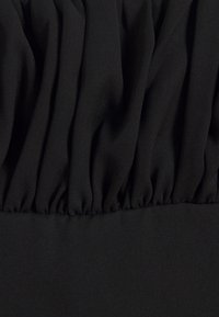 Tessuto nero con pieghe arricciate, che mostra una consistenza morbida e liscia. Il design presenta pieghe orizzontali sulla superficie del tessuto.