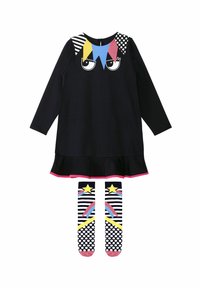 Vestido negro de manga larga con patrón geométrico colorido en los hombros; dobladillo con volantes. Combinado con calcetas a rayas en blanco y negro con estrellas.