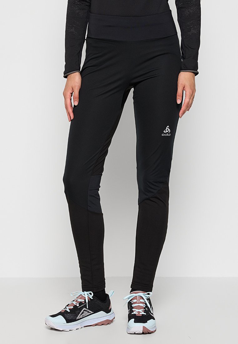Schwarze Sportleggings mit hohem Bund, aus glattem dehnbarem Stoff gefertigt, mit seitlichen Einsätzen und einem dezenten Logo nahe dem Saum.