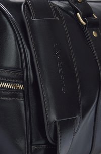 Czarna skórzana torba o połyskującej powierzchni, z kieszenią na zamek, złotymi elementami, wytłoczonym logo oraz kontrastowym przeszyciem wzdłuż brzegów.