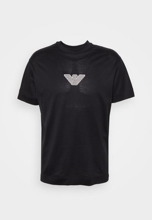 Czarny t-shirt z krótkim rękawem wykonany z gładkiego materiału, z srebrnym logo w kształcie stylizowanego orła na piersi.