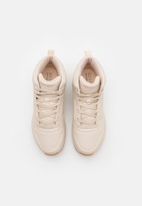 Scarpe da ginnastica beige con tomaia in pelle liscia, dettagli perforati, lacci piatti e suola in gomma marrone chiaro.