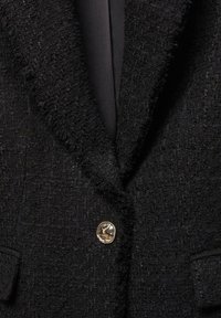 Schwarzer, strukturierten Blazer mit Reverskragen, zwei vorderen Taschen und glänzenden goldenen Knopfverschluss. Glatte Innenauskleidung.