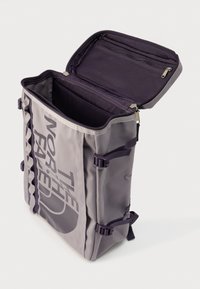 Γκρι σακίδιο με δομημένο σχέδιο, κατασκευασμένο από ανθεκτικό ύφασμα. Διαθέτει επάνω φερμουάρ, εσωτερικά διαμερίσματα και ρυθμιζόμενους ιμάντες.