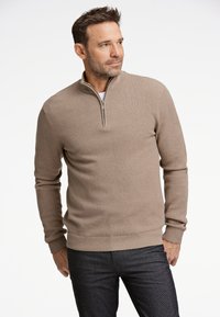 Suéter marrón con cremallera, de patrón texturizado, mangas largas y dobladillo acanalado, combinado con pantalones oscuros.