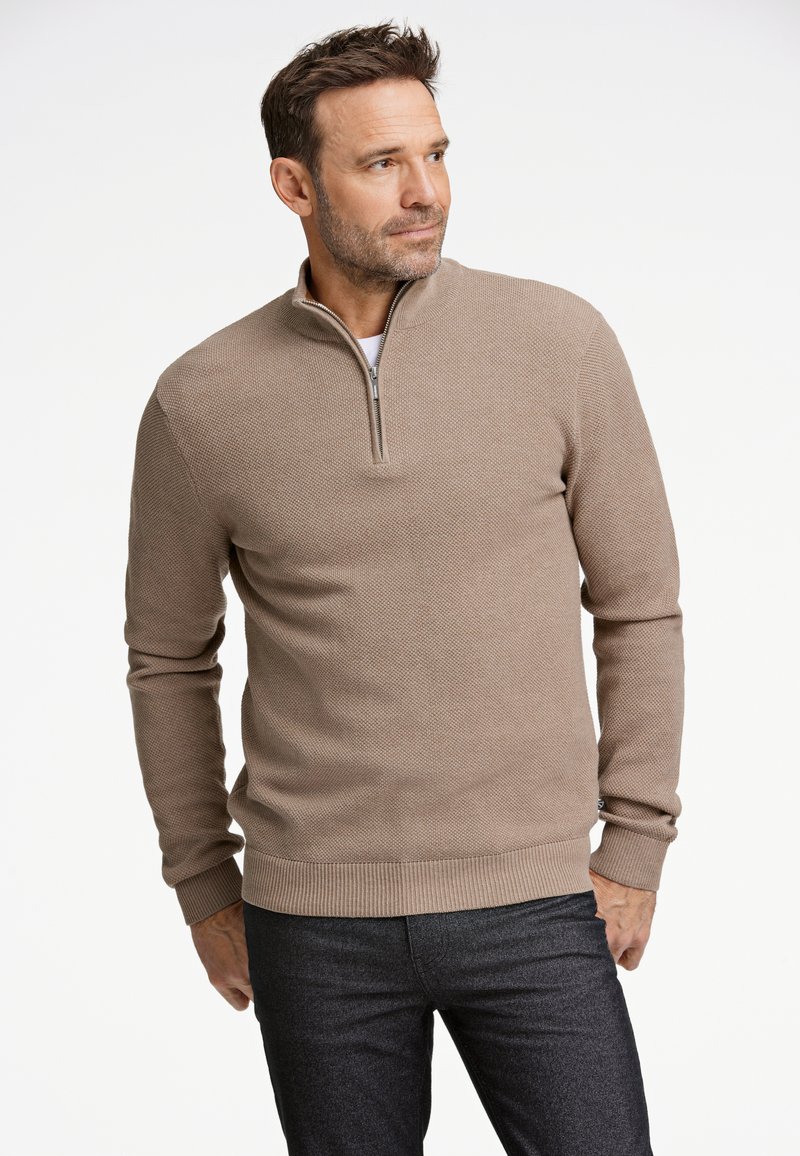 Suéter marrón con cremallera, de patrón texturizado, mangas largas y dobladillo acanalado, combinado con pantalones oscuros.