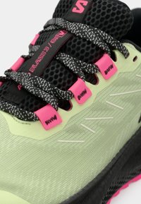 Αθλητικό παπούτσι ανοιχτού πράσινου με υφή στην επιφάνεια, άνω μέρος από μαύρο δίχτυ, ροζ λεπτομέρειες και μαύρα κορδόνια με σχέδιο. Διαθέτει μαλακή σόλα.