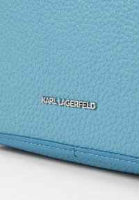 Geantă din piele texturată albastră cu un logo argintiu „KARL LAGERFELD” și detalii cu cusături contrastante.