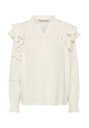 Balta blūze ar volānu piedurknēm, teksturētu audumu un caurumotu dekoru apkārt apkaklei un aprocēm. Brīvs siluets ar V veida izgriezumu.