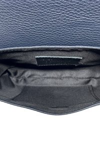Interno della borsa in pelle blu navy, caratterizzato da una texture liscia e una fodera in tessuto nero. Include una piccola etichetta con testo impressa.
