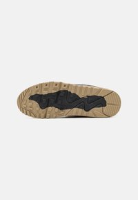 Podošva Nike topánky so vzorom z čiernej gumy pre trakciu, polstrovaná medzipodrážka v béžovej farbe a textúrovaný dizajn gripu, s logom značky.