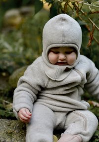Svijetlosiva flis skijaška odijela s kapuljačom i patentnim zatvaračem. Sadrži rebraste detalje i mekan, teksturirani završetak. Pogodno za nošenje na otvorenom.