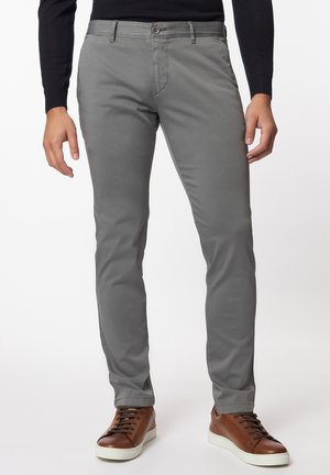 Graue Baumwollhose im Slim-Fit mit detaillierten Nähten, Vordertaschen und Knopfverschluss, getragen mit braunen Sneakern mit weißen Sohlen.