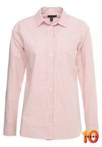 Chemise à rayures rouges et blanches à manches longues avec un col boutonné, une poche avant et des boutons blancs, fabriquée en tissu lisse.