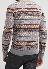 Maglione grigio con motivi geometrici colorati in rosso, giallo e blu. Maniche e orlo a coste, design aderente e texture in maglia leggera.