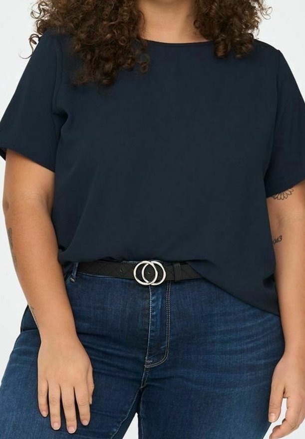 Haut bleu marine à manches courtes, coupe décontractée, associé à un jean en denim foncé et une ceinture noire avec deux anneaux argentés.
