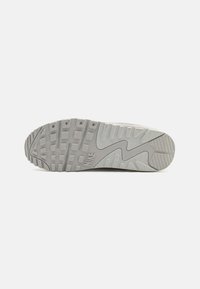 Nike sneaker outsole featuring a grey rubber material, textured surface with square and zigzag patterns, and logo detail near the heel.