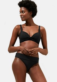 Zwarte bikini-set met een gedraaide detail op het bovenstuk, verstelbare bandjes en een mid-rise broekje met een brede tailleband. Soepele textuur.