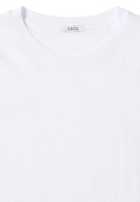Camiseta blanca de algodón con cuello redondo y una etiqueta que dice "CECIL" cerca del cuello. Textura suave con un detalle de costura mínimo.