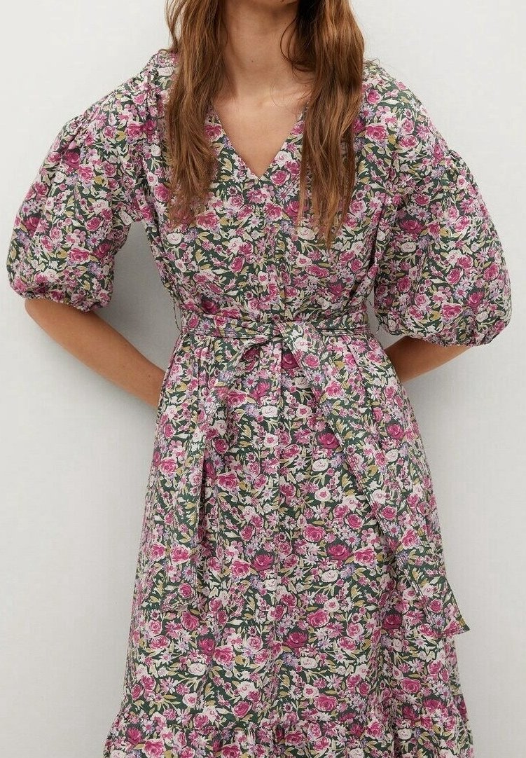 Robe imprimée florale avec manches bouffantes, décolleté en V et taille à nouer. Les motifs comprennent des fleurs roses et blanches sur un fond vert foncé.