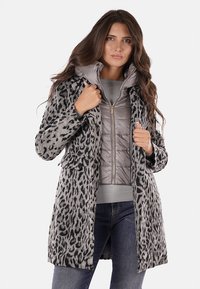 Abrigo de estampado de leopardo en tonos de gris, con una capa de acolchado con cremallera debajo, bolsillos frontales y una silueta estructurada.
