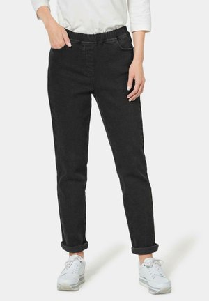 Zwarte denim joggings met een elastische tailleband, twee voorzakken, opgerolde manchetten en een tappende pasvorm, gecombineerd met witte sportschoenen.