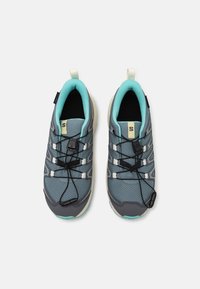 Gray athletic shoes with mesh upper, turquoise accents, elastic laces, and pull tabs. Textured rubber sole for grip.