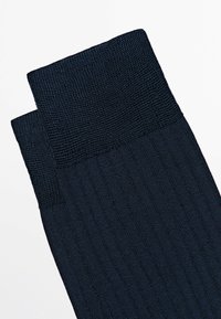 Zwei marineblaue, gerippte Socken mit strukturierten Bündchen, flach auf einem weißen Hintergrund liegend.