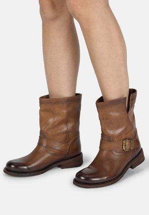 Braune Leder-Ankle Boots mit einer Schnallenakzent, einem niedrigen gestapelten Absatz und einem lässigen Schaft mit einer strukturierten Oberfläche.