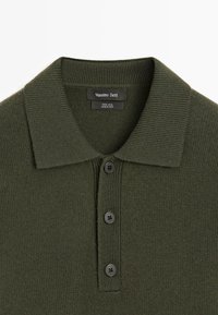 Ciemnozielony wełniany sweter polo z prążkowanym kołnierzykiem, trzema czarnymi guzikami i metką z napisem "Massimo Dutti". Teksturowany i starannie wykończony.