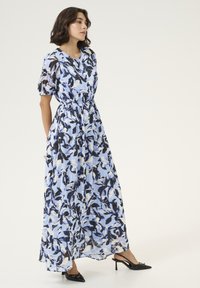 Robe maxi en tissu léger, avec un motif floral bleu et noir, taille élastique, manches courtes bouffantes et une silhouette fluide.
