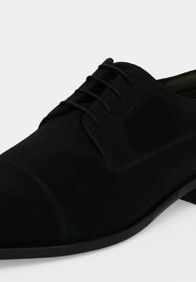 Chaussure Oxford formelle noire avec laçage fermé, bout droit et semelle en cuir lisse sur fond blanc.