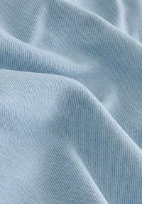 Lichtblauwe stof met een fijne geribbelde textuur, met zachte plooien en een subtiele glans, geschikt voor kleding of meubeltoepassingen.