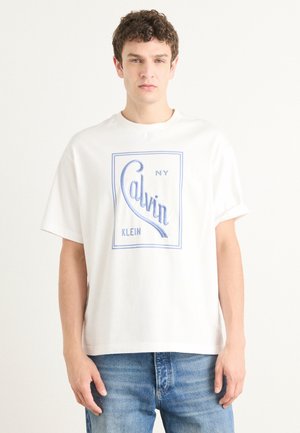 White cotton t-shirt with short sleeves, featuring a blue graphic logo reading "Calvin Klein" and "NY" in a rectangular frame.