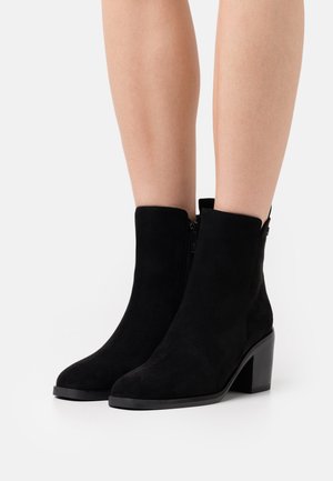 Black suede ankle boots with a square toe, side zipper, and a chunky heel, featuring a smooth texture and minimal design.