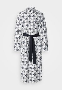 Abito camicia bianco con un motivo geometrico nero, maniche lunghe, patta dei bottoni e una cintura scura coordinata in vita.