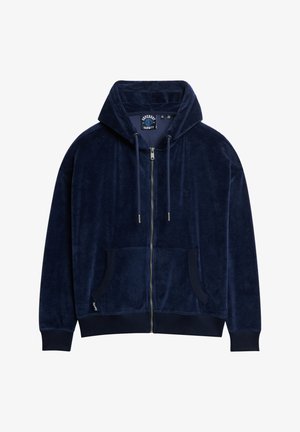 Granatowa bluza z kapturem na zamek, wykonana z miękkiego weluru, z kieszenią kangurką i ściągaczami przy mankietach. Posiada regulowany kaptur na sznurku oraz logo na piersi.