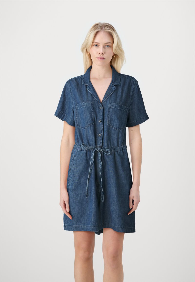 Abito camicia in denim con maniche corte, chiusura a bottoni, due tasche sul petto, vita aderente e lunghezza sopra il ginocchio in blu scuro.