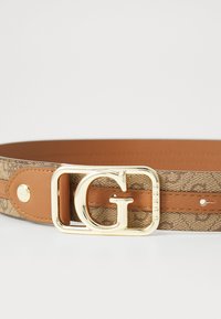 Cintura con motivo marrone e retro in pelle beige. Presenta una fibbia dorata a forma di G con logo inciso e dettagli di rivetti coordinati.