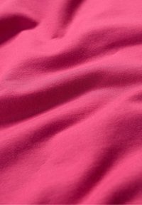 Vervaagd roze katoenstof met een gladde, licht getextureerde oppervlakte, die zachte plooien en kreukels toont. Eenvormige kleur door de stof.