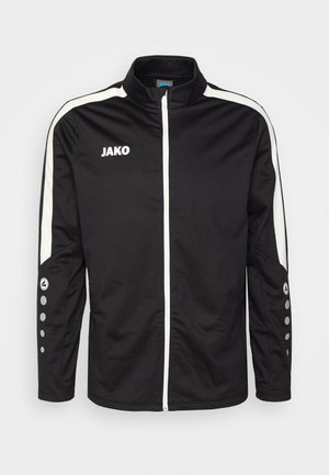 Black sports jacket with a high collar, white side stripes, and JAKO logo. Features zip closure and textured fabric with circular accents on sleeves.