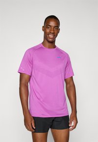 Pink athletic t-shirt with short sleeves, featuring a textured pattern on the front and a blue Nike logo on the chest. Worn with black shorts.