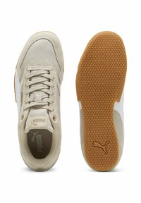 Beżowe skórzane i zamszowe sneakersy z białymi akcentami i podeszwą z gumy. Posiadają fakturowaną powierzchnię i sznurowany design.